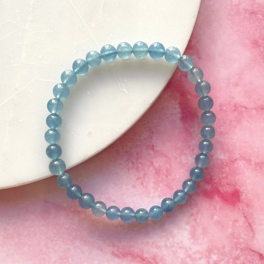 Pale blue aquamarine bead bracelet on a pink surface