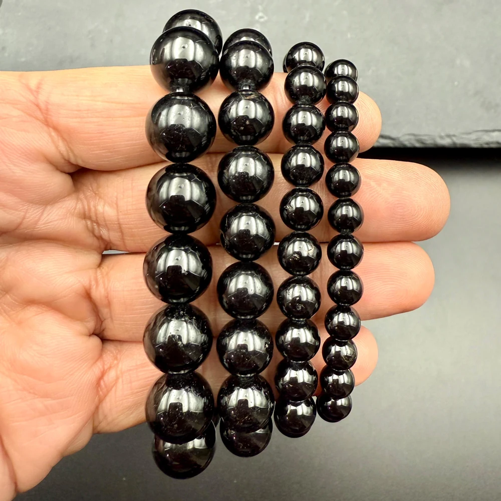 Black onyx bracelets in several bead sizes resting in a hand